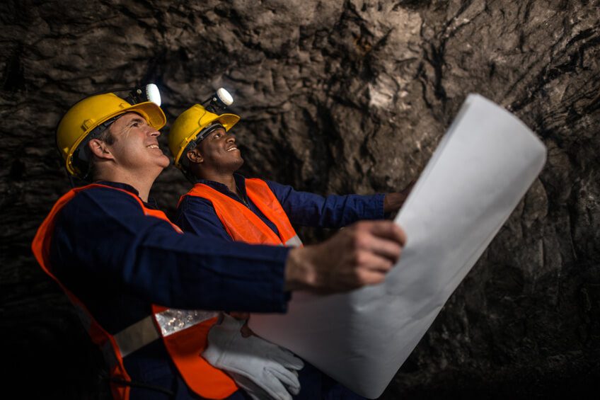 Miners working at the mine holding a blueprint Miners working at the mine holding a blueprint